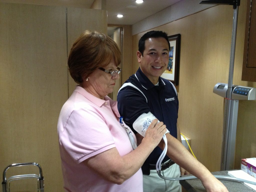 Kenneth C. Wong having his blood pressure checked by a nurse inside a mobile community health unit